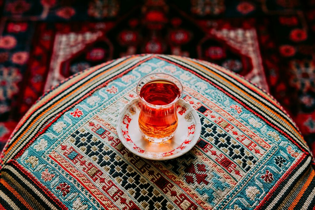 İnce belli bardakta demli çay, işlemeli bir örtünün üzerinde
